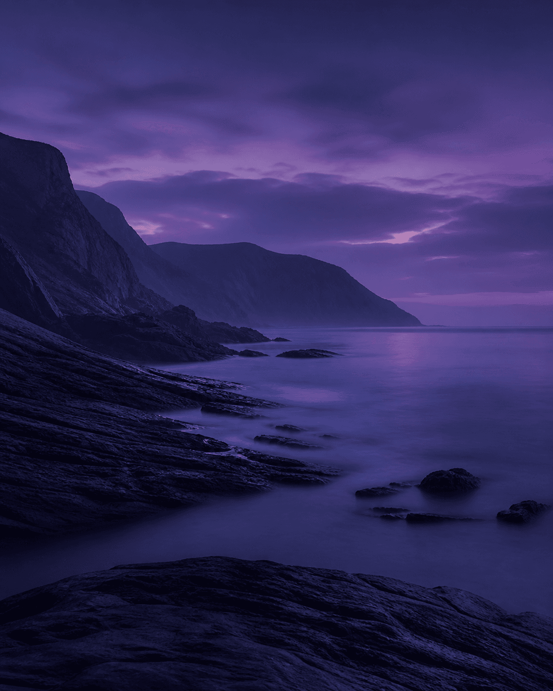 Dark coastline beneath a violet evening sky